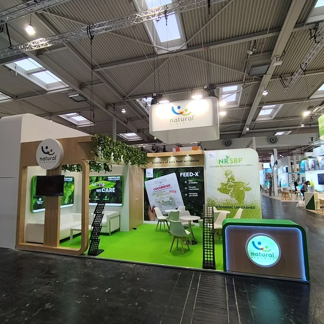 Natural Remedies stand at EuroTier 2024 showing the suspended illuminated logo box and foliage canopy