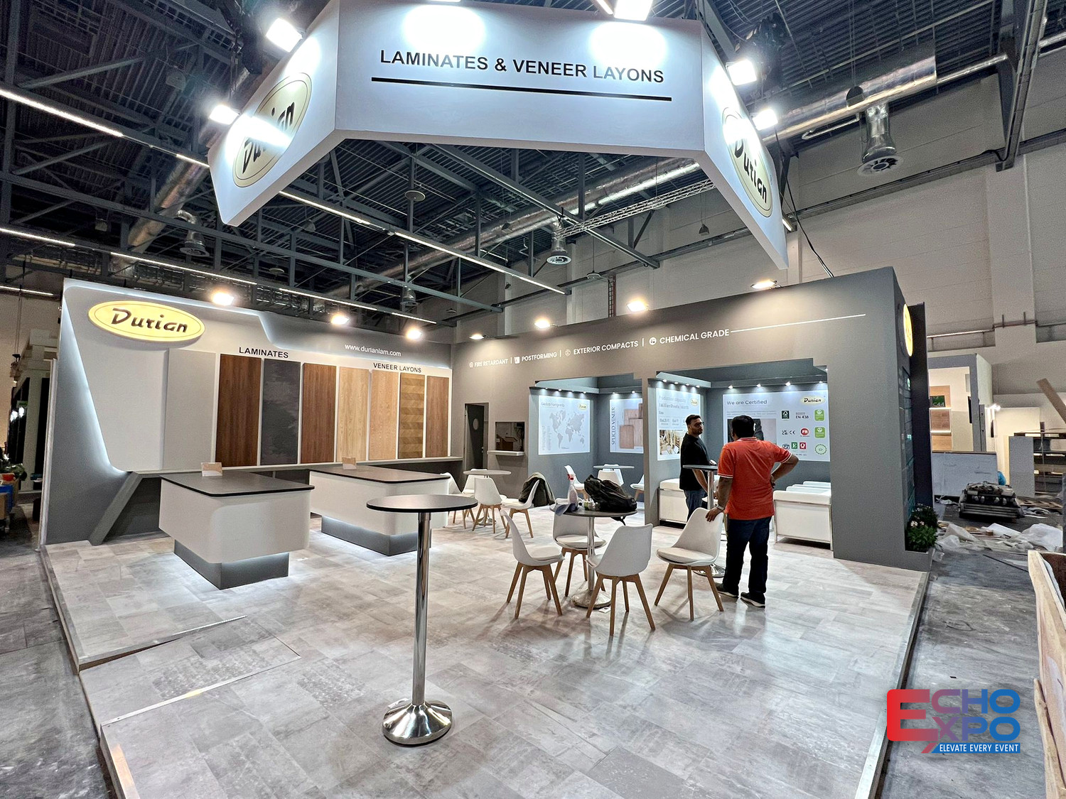 Durian Laminates exhibition stand at interzum Cologne 2025, with a suspended oval halo sign, laminate sample walls and open meeting seating.
