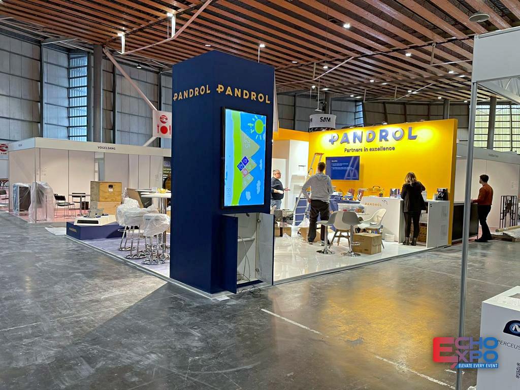 PANDROL exhibition stand at SIFER Lille 2023, with a navy tower carrying a portrait screen and a yellow branded back wall behind the meeting area.