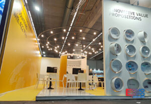 EVA Pharma 78 m² exhibition stand at CPHI Frankfurt 2022, with a yellow angled brand wall, suspended circular light rings and a product display wall of recessed circular vitrines.