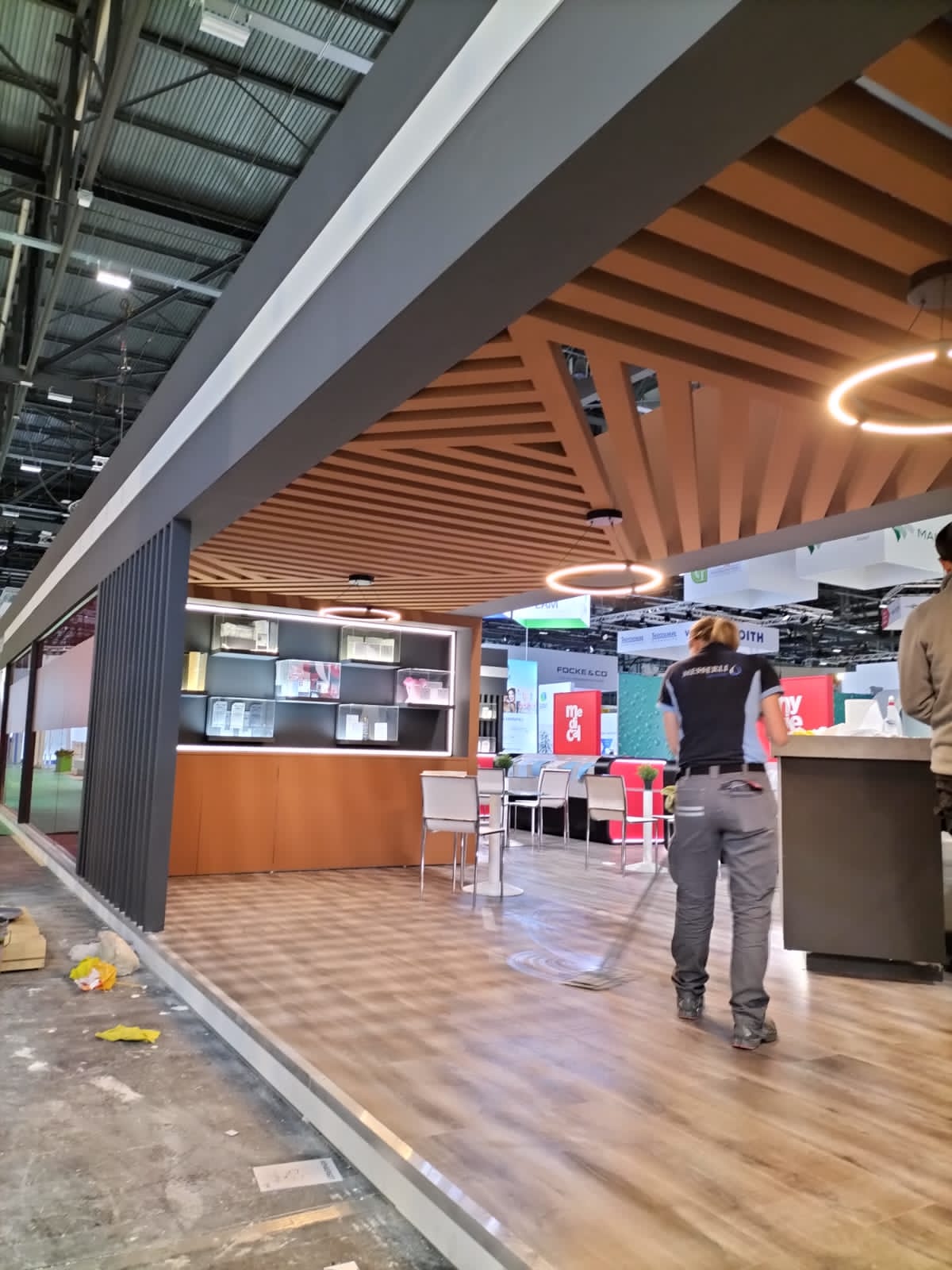 Timber slatted ceiling, lit product display shelving and bar seating inside a nonwovens exhibition stand at INDEX, Palexpo Geneva, April 2023