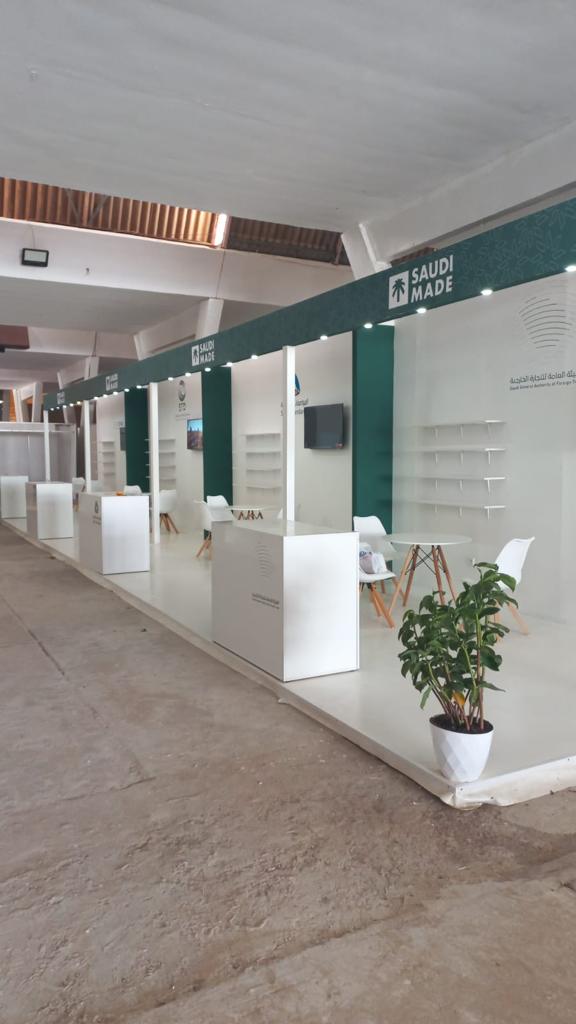 National pavilion at the OIC Member States Trade Fair in Dakar, with a continuous branded fascia over a row of identical booths, each with shelving, a counter, a screen and seating