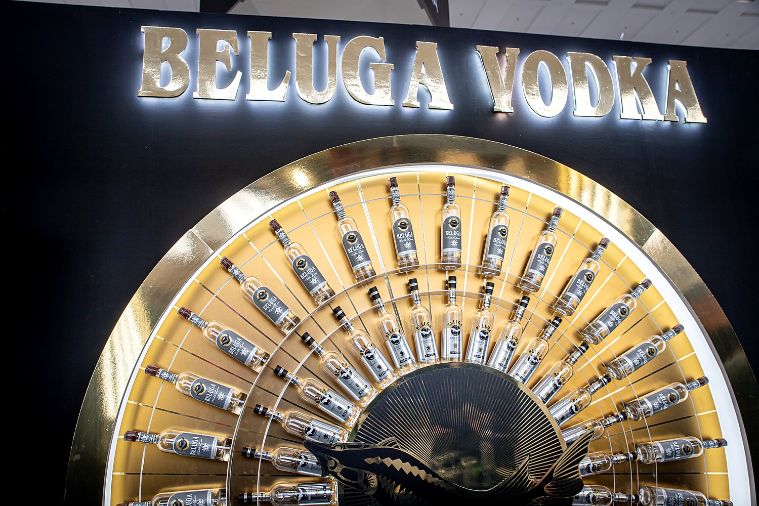 Close view of the Beluga Noble Vodka sunburst wall at Bar Convent Berlin: rows of vodka bottles set radially in a backlit gold half-circle beneath the BELUGA VODKA sign.