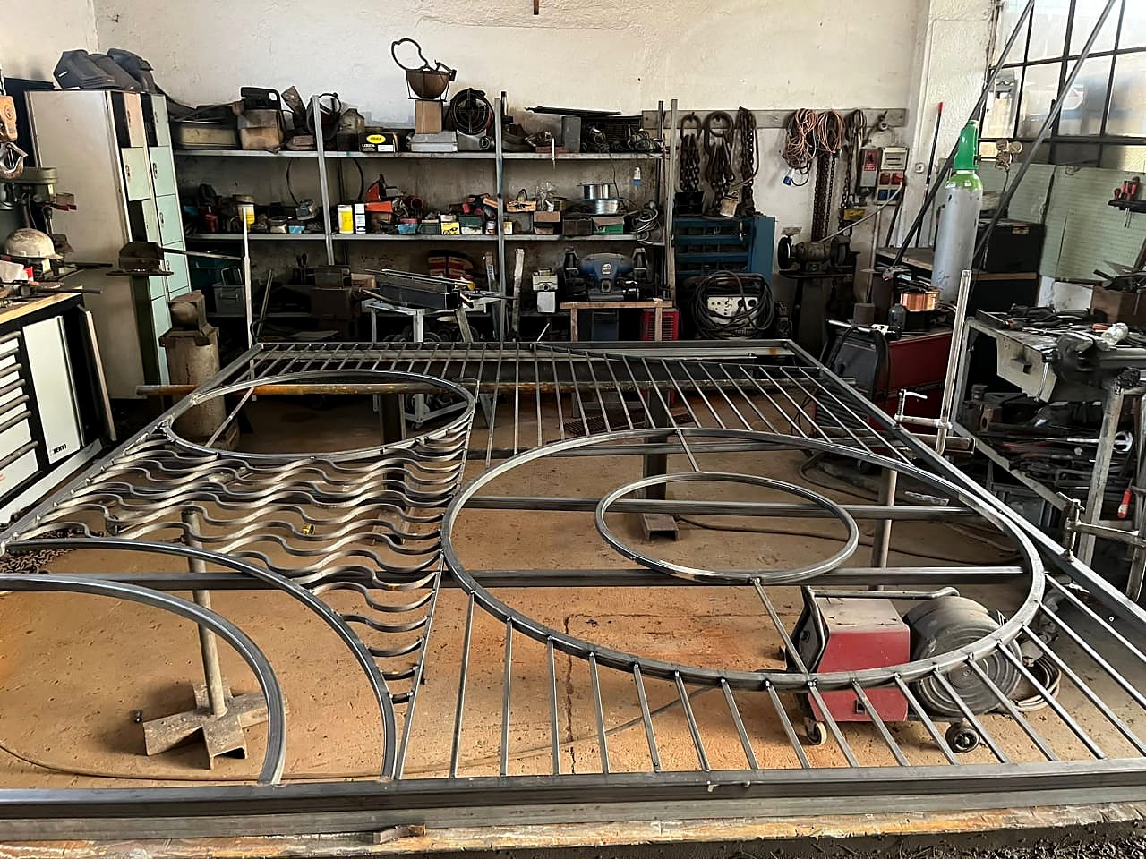 The steel frame of the Beluga sunburst wall being fabricated on a workshop floor, with radial bars and circular sections welded in place.