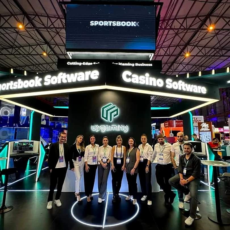 The UPGAMING team standing together on their stand at SiGMA Europe 2023 in Malta, under the Sportsbook Software and Casino Software header.