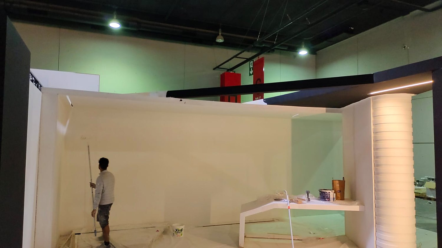 The VICE stand under construction at Messe Frankfurt in September 2022, with a painter finishing the white interior walls and the ribbed column in place.