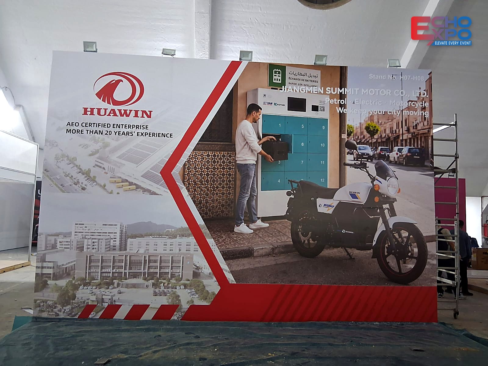HUAWIN back wall finished during build-up: printed graphics with the company logo and motorcycle imagery, EVS Mobility Expo Morocco 2026.