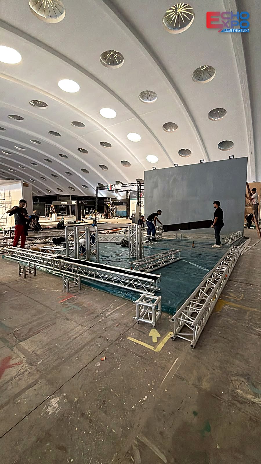 Build-up of the WANGYE Motorcycle stand at OFEC Casablanca: 30 cm aluminium truss sections laid out on the protected floor before lifting, EVS Mobility Expo Morocco 2026.